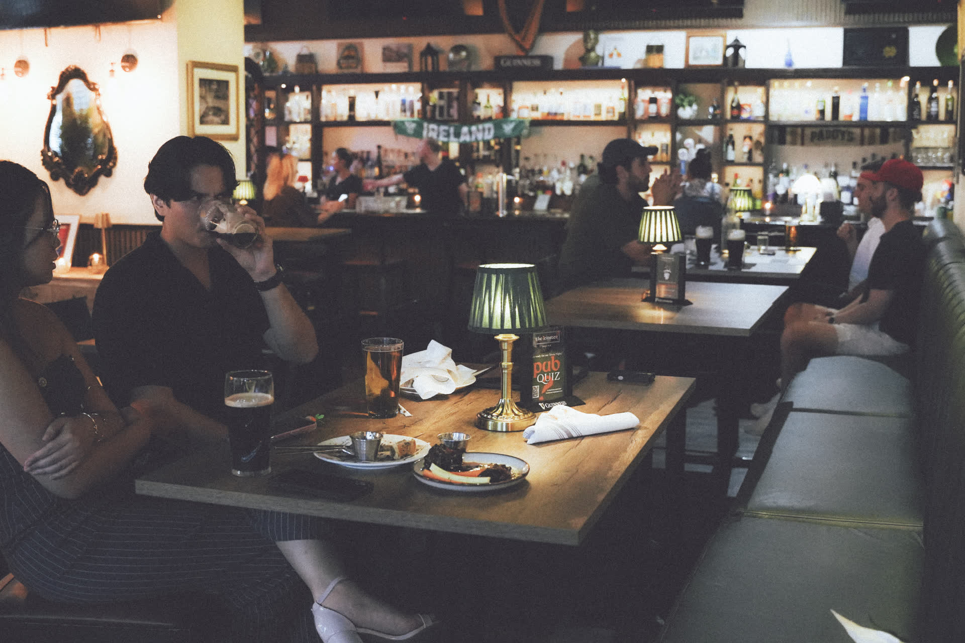 Guests enjoying pints of Guinness and Irish pub food inside The Leinster Miami with Ireland banner